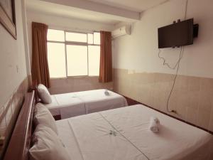 a room with two beds and a tv on the wall at Hotel Aloe Uka in Iquitos