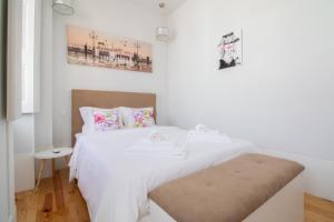 - une chambre blanche avec un lit blanc et un banc dans l'établissement Passeio da Avenida - Central Avenue Apartment with Elevator, à Viana do Castelo