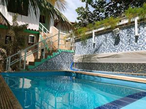 a swimming pool with blue tiles and stairs next to a building at Pousada da Pedra in Pedra de Guaratiba