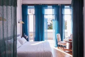 1 dormitorio con cortinas azules, 1 cama y balcón en Cocorico Luxury House - Porto, en Oporto