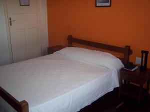 a bedroom with a white bed with a wooden headboard at Hotel Termópolis in Termópolis +99 photos