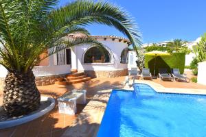 a house with a palm tree next to a swimming pool at Casa Mozart in Jávea