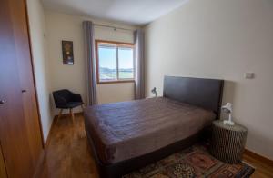 ein Schlafzimmer mit einem Bett, einem Stuhl und einem Fenster in der Unterkunft Afife T2 - Bouça Cabrita Residence in Afife