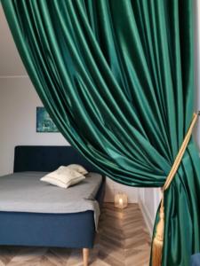 a bedroom with a bed with a green curtain at Cosy center Apartment in Klaipėda +19 photos