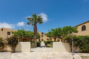 eine Palme vor einem Gebäude in der Unterkunft La Tonnara di Bonagia Resort in Valderice