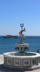 a statue of a bird and a cross in front of the water at Roses Studios in Karpathos