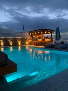 uma grande piscina à noite com um bar em Apiro Mykonos em Míconos