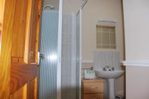 y baño con lavabo y ducha acristalada. en Kemar House, en Belmullet