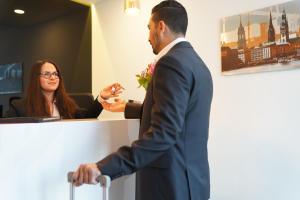 Un hombre de traje parado en un escritorio con una mujer en Hotel Dias, en Pinneberg