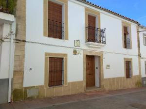 - un bâtiment blanc avec des fenêtres et une porte dans l'établissement Apartamentos Rurales Tía María, à Mata de Alcántara