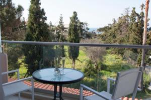 a glass table and two chairs on a balcony with a view at Mojito Elegant Studios in Plataniás
