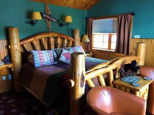 1 dormitorio con cama de madera y silla en Lake George Boathouse Waterfront Lodging en Bolton Landing