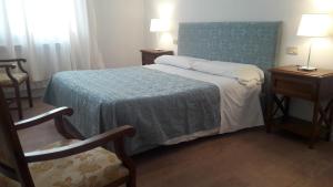 a bedroom with a bed and two tables and a chair at Il Grifo Camere e Suites in Grosseto