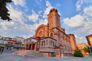 a large brick building with a clock tower at Central Square Family Apartment in Nea Kallikrateia
