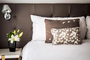 a bed with pillows and a vase of flowers on it at Flaat Recoleta Plaza in Buenos Aires +28 photos