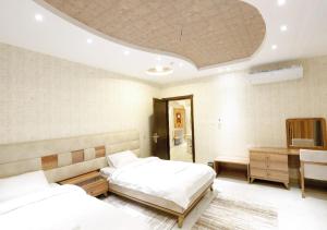 1 dormitorio con 2 camas, escritorio y cama sidx sidx sidx sidx en Four Seasons Suites, en Taif