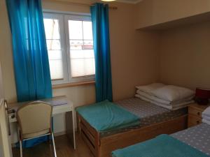 a bedroom with two beds and a desk and a window at Apartamenty Turkusowe in Rowy