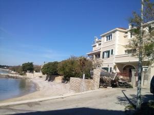 a large white building next to a beach at Studio Apartment Mala plaža in Kaštela