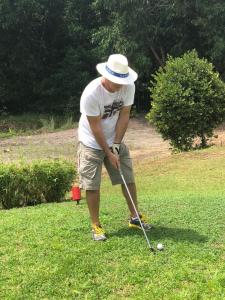 a man in a hat playing golf in the grass at Hotel Coucoue Lodge in Assinie
