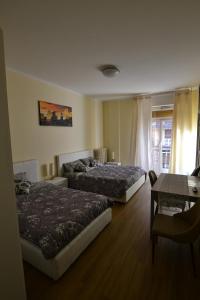 a hotel room with two beds and a table and a desk at B&B Lidiya in Bologna