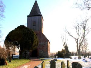 una vieja iglesia con una torre en un cementerio en Haus Ketzenberg 1 - Lütt Mööv, en Groß Zicker