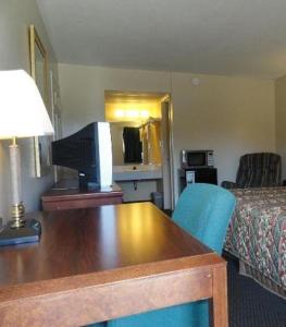 a hotel room with a desk and a bed at Red Carpet Inn (formerly Royal Inn) in Terre Haute