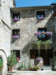 un edificio de piedra con flores en las ventanas en La Corralata, en Biescas