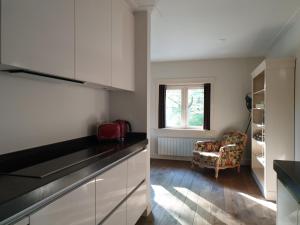 una cocina con armarios blancos, una silla y una ventana en Studio in Stijl, en Apeldoorn
