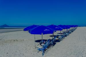 eine Reihe blauer Stühle und Sonnenschirme am Strand in der Unterkunft Beach Hotel Juquehy in Juquei