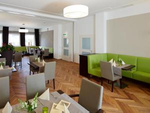 un restaurante con muebles verdes, mesas y sillas en Hotel Karolinger Hof en Lorsch