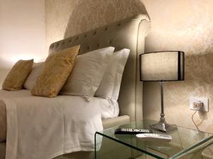 a bed with pillows and a glass table with a lamp at Dimora San Biagio Suites&Apartment in Lecce