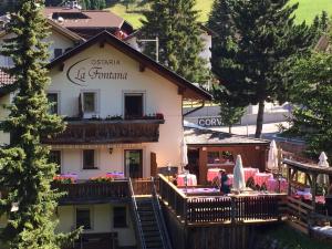a building with a balcony and a patio in front of it at Ostaria La Fontana in Corvara in Badia
