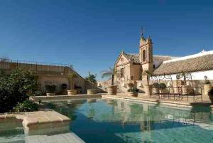 a large swimming pool with a large stone building at Hospedería del Monasterio in Osuna