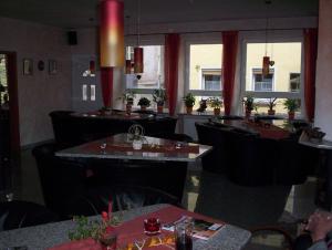 a restaurant with black chairs and tables and windows at Zum Belzenikel in Dernbach