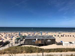 a beach with a building and a lot of people at De Strandmus in Egmond aan Zee