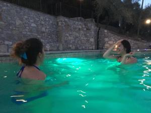 two women in a swimming pool at night at Villa D'Arte Agri Resort in Pontassieve