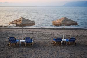 a group of chairs and umbrellas on a beach at Mesogios Beach in Kissamos