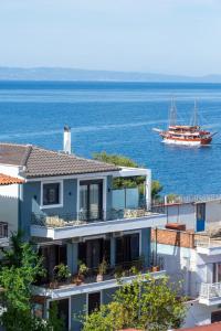 a boat in the water next to a house at Pela Veranda Exquisite Suites in Neos Marmaras