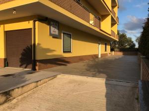 un bâtiment jaune avec un parking à côté dans l'établissement B&B La Casa di Violetta, à Acconia