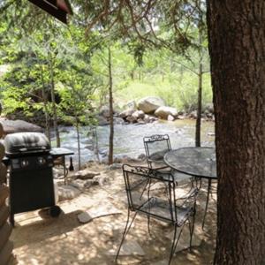 a patio with a table and chairs next to a tree at Swiftcurrent Lodge in Estes Park