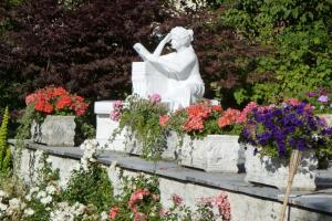 Une statue d'une femme assise dans un bouquet de fleurs dans l'établissement Ferienhaus Kramser, à Arnoldstein