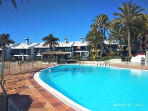 duży basen z palmami i budynkami w obiekcie Apartment Sun Club w mieście Playa del Aguila