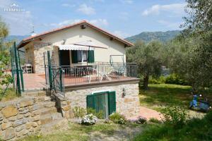 ein kleines Steinhaus mit Balkon und Sonnenschirm in der Unterkunft Casa Delle Olive in Dolceacqua