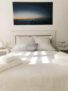 białe łóżko z białymi poduszkami i zdjęciem na ścianie w obiekcie TERUEL CON AMOR w mieście Teruel
