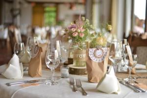 a table with a white table cloth and wine glasses at Landhaus Müllenborn in Gerolstein