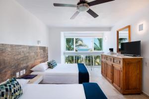 a bedroom with two beds and a flat screen tv at Hotel Villa Varadero in Nuevo Vallarta 