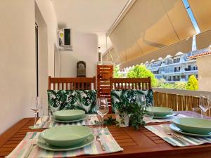 a wooden table with green plates and glasses on a balcony at Relax Apartment in Perea