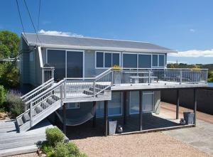 a large house with a large deck with a porch at Bayview Retreat in Oneroa