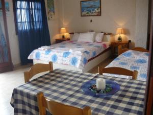 a bedroom with two beds and a table with a candle on it at Villa Victoria in Makry Gialos