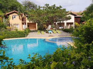 a pool at a resort with chairs and trees at Condominio Villa Hermosa in Playa Hermosa